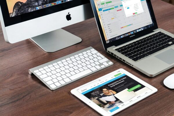 Estrategia SEO fácil para un buen posicionamiento web A sleek office desk setup featuring Apple devices: iMac, MacBook, and iPad.