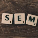 Wooden background with letter tiles spelling SEM, representing search engine marketing.