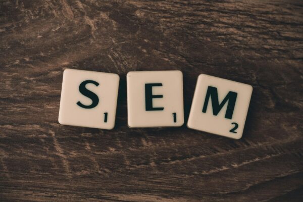 Qué es SEM: search engine marketing Wooden background with letter tiles spelling SEM, representing search engine marketing.